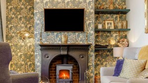 A living room with a fireplace, a television mounted above it, and patterned wallpaper. - 2 Bed in Bakewell (oc-88661) (Bakewell)