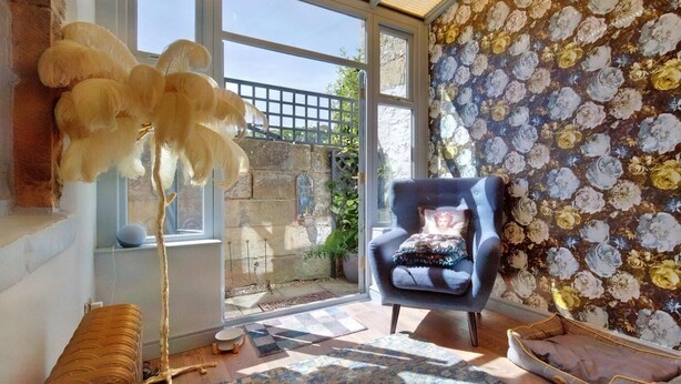 A room with a large window, a blue armchair, a patterned rug, and a decorative wall. - 2 Bed in Bakewell (oc-88661) (Bakewell)