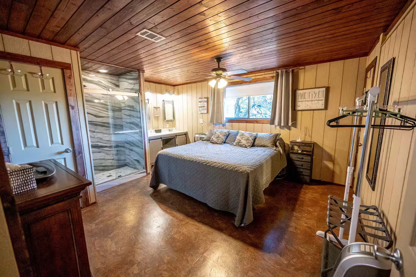 Un dormitorio con cama, ducha, tocador y ventana.