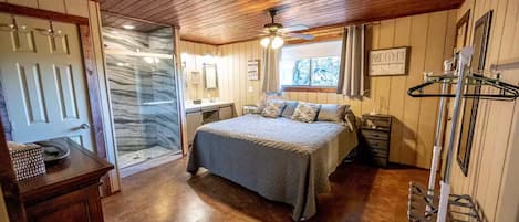 Un dormitorio con cama, ducha, tocador y ventana.