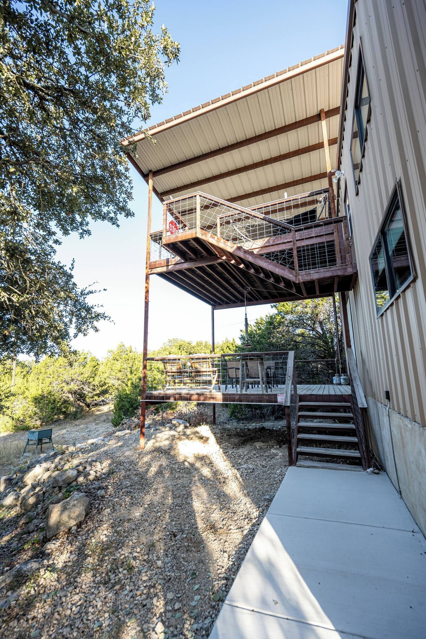 Un edificio con un espacio al aire libre techado, una escalera y un cerramiento.