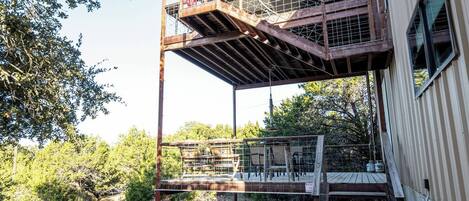 Un edificio con un espacio al aire libre techado, una escalera y un cerramiento.