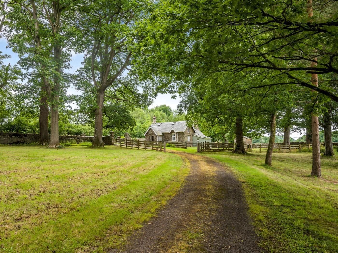 Ein ländliches Anwesen mit einem Steinhaus, einem umzäunten Garten und einem Feldweg, der zum Haus führt.