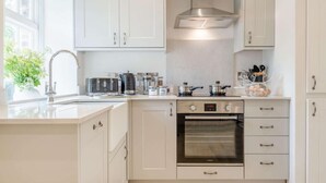 A modern kitchen with white cabinets, a stainless steel range hood, a built-in oven, and a window with a view of greenery. - 1 Bed in Brecon (oc-88748) (Trallong)