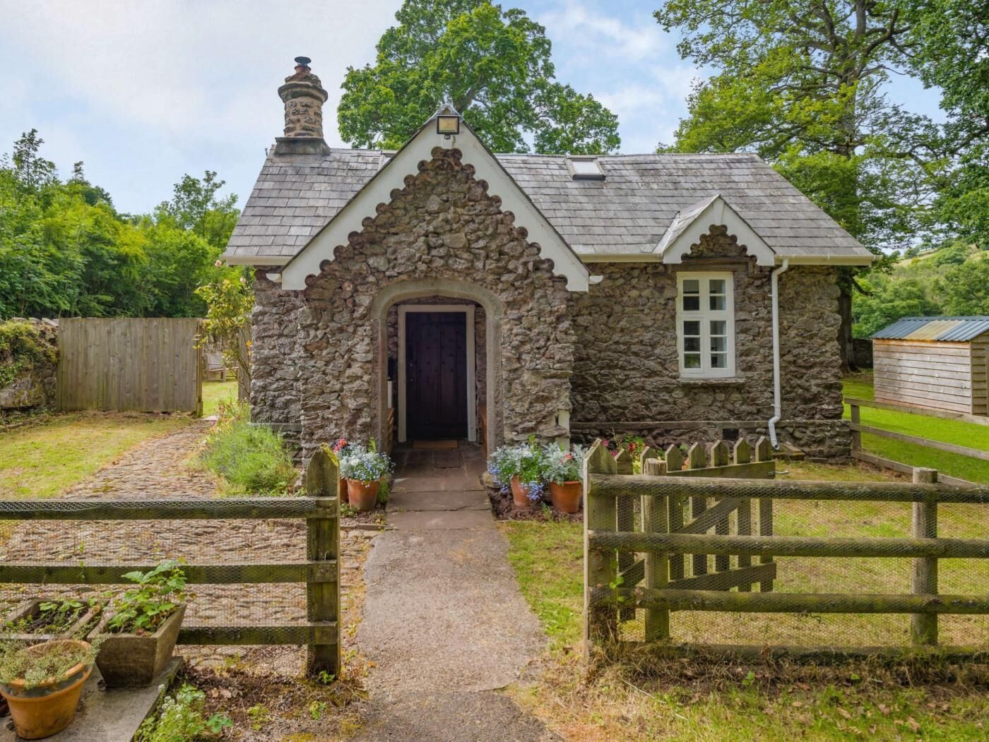 Une petite maison en pierre avec une porte en bois, une petite fenêtre et une cheminée en pierre.