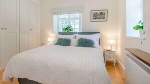 A bedroom with a bed, bedside tables, a window with a view, a radiator, and a wardrobe. - 1 Bed in Brecon (oc-88748) (Trallong)
