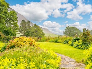 A garden with a stone pathway, lush greenery, and a mountain in the background. - 3 Bed in Cockermouth (oc-88773) (Buttermere)