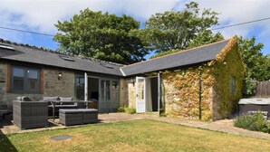 A house with a stone exterior, a covered patio with outdoor furniture, and a grassy yard. - 2 Bed in Ventnor (oc-88857) (Niton)