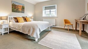 A bedroom with a bed, bedside tables, a desk, a chair, a radiator, and a window. - 2 Bed in Ventnor (oc-88857) (Niton)