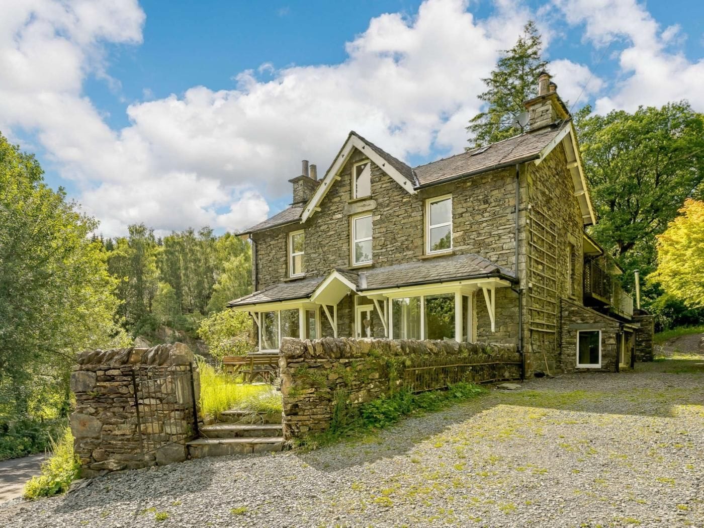 A stone house with a porch and a stone staircase leading to the entrance.