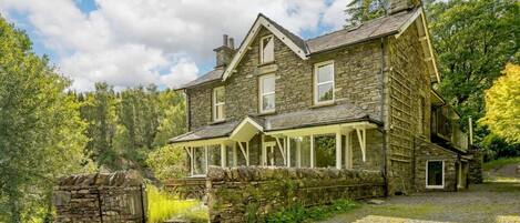 A stone house with a porch and a stone staircase leading to the entrance.