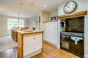A kitchen with a wooden island, white cabinets, a microwave, and a stove. - 3 Bed in Ambleside (oc-88769) (Claife)