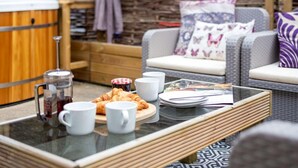 A cozy outdoor seating area with a coffee table, croissants, and a French press. - 2 Bed in Launceston (oc-88859) (Saint Giles on the Heath)