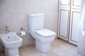 A bathroom with a toilet, bidet, and cabinet. - Room-luxurious Room - D (Johannesburg)