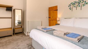 Un dormitorio con cama, armario, espejo, radiador, puerta de madera y un adorno en la pared.