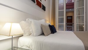 A hotel room with a bed, a bedside table with a lamp, and a view of the outside through a window. - CM17 Excellent location in the heart of Seville. Large terrace (Ciudad Sevilla)