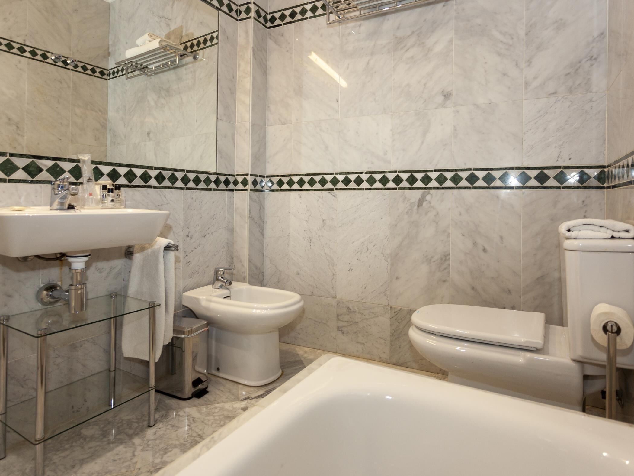 Un baño con lavamanos de cristal, un bidé, un inodoro y una bañera.