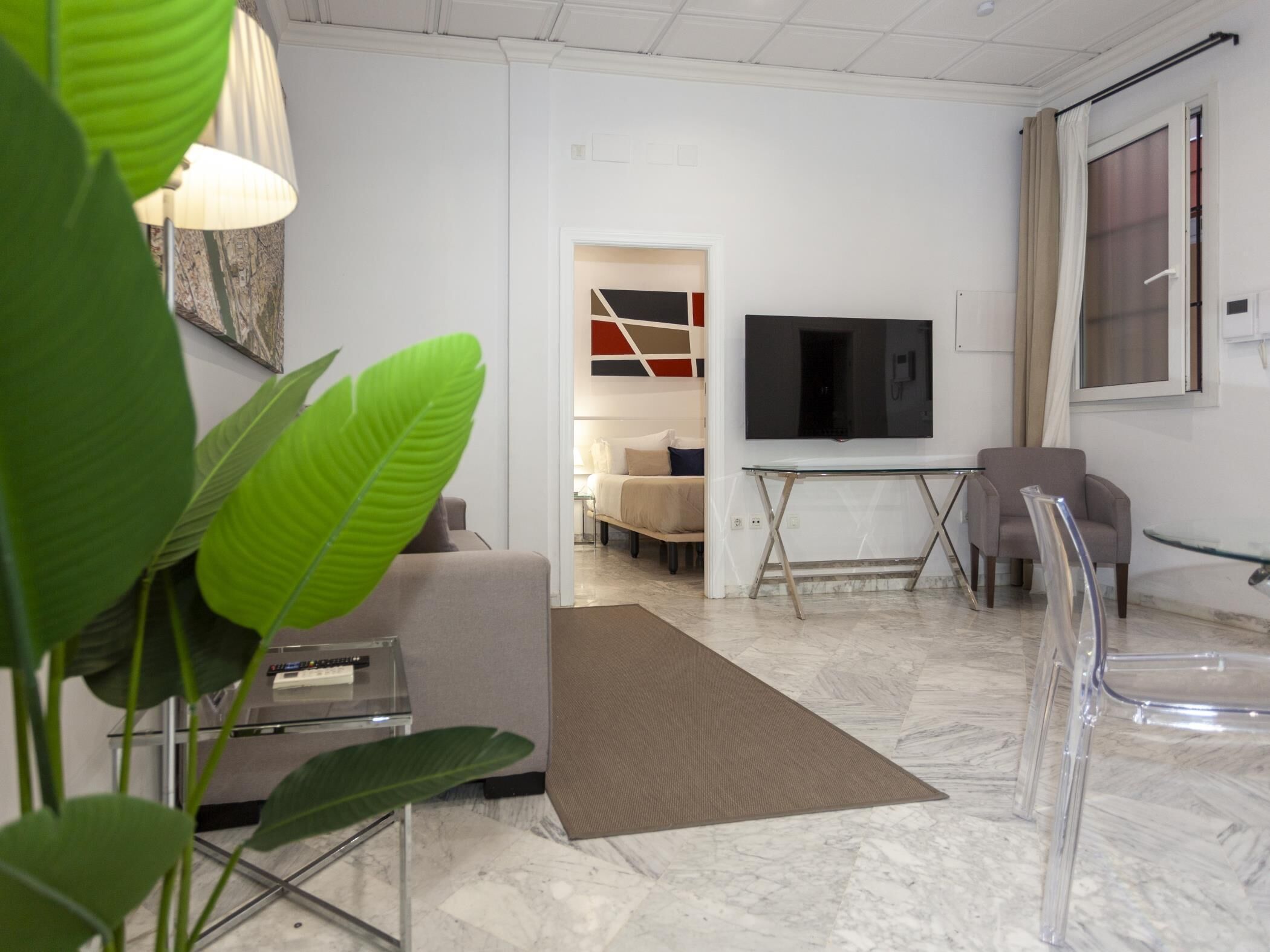 Una sala moderna con un sofá, televisor y una mesa de centro de vidrio.