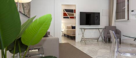 Una sala moderna con un sofá, televisor y una mesa de centro de vidrio.