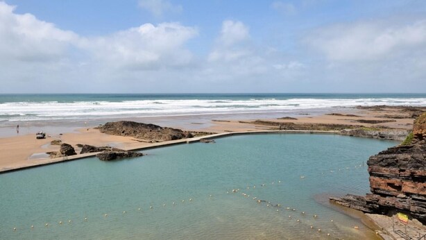 A coastal landscape with a clear blue sky, a sandy beach, and a rocky pool area. - 3 Bed in Launceston (oc-88858) (Saint Giles on the Heath)