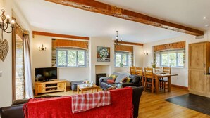 A spacious living room with a fireplace, a dining area, and a kitchen. - 3 Bed in Launceston (oc-88858) (Saint Giles on the Heath)