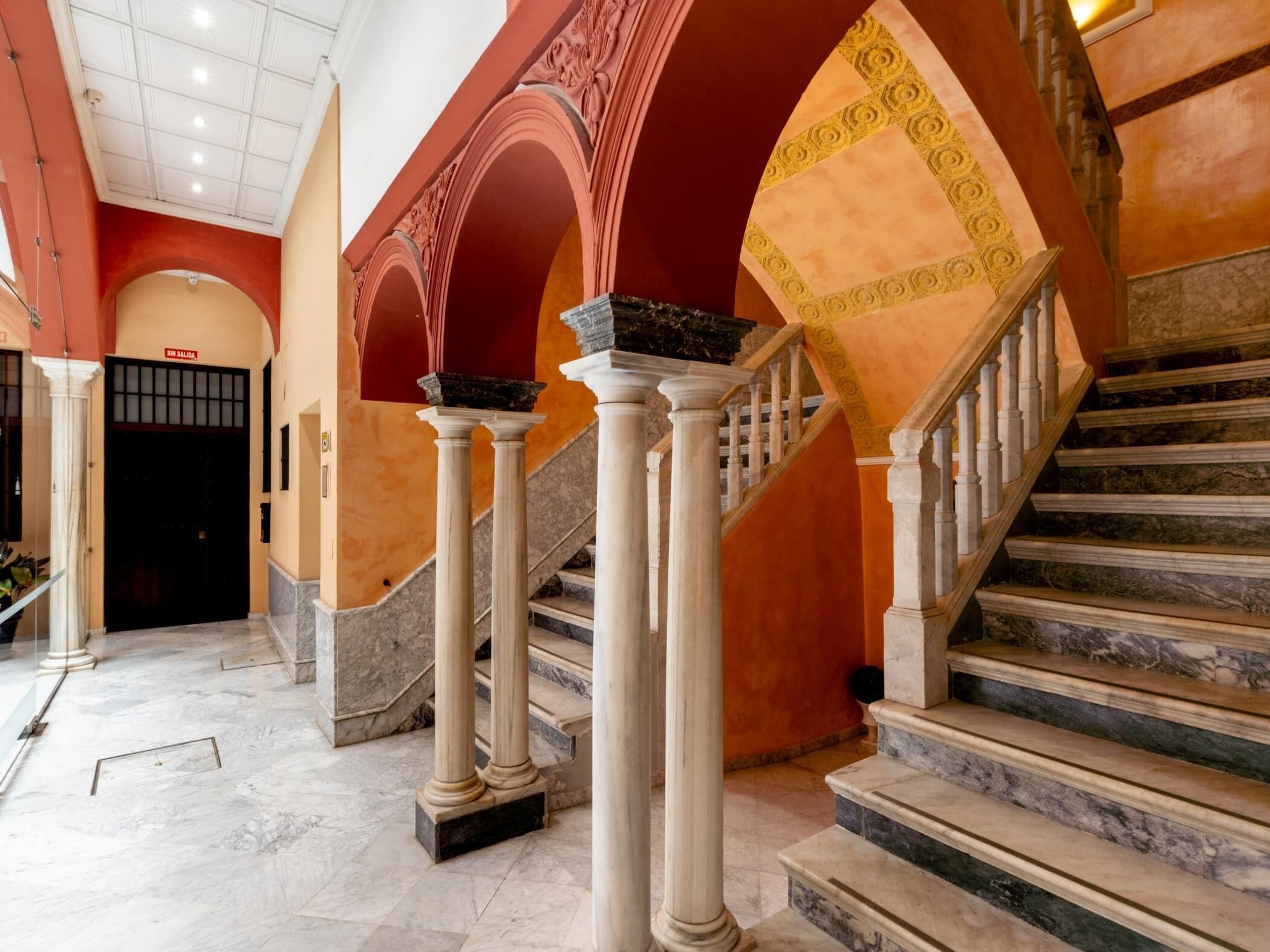 A grand staircase with marble steps and white columns, leading to an upper level.