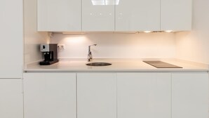 Una cocina moderna con armarios blancos, una cafetera, un fregadero y una encimera.