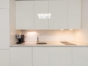 Eine moderne Küche mit weißen Schränken, einer Kaffeemaschine, einem Spülbecken und einer Arbeitsplatte.