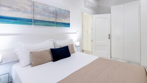 Un dormitorio con una cama, un armario y un cuadro de una playa.