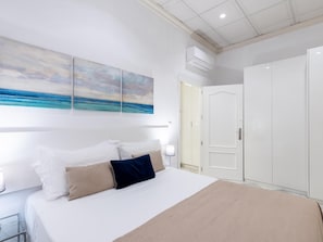 Ein Schlafzimmer mit Bett, Kleiderschrank und einem Gemälde einer Strandansicht.