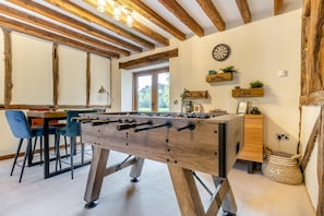 A room with a foosball table, bar stools, a dartboard, and wooden beams on the ceiling. - 4 Bed in Oswestry (oc-88850) (Morda)