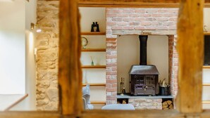 Un intérieur rustique avec une cheminée en briques, des étagères en bois et un mur en pierre.