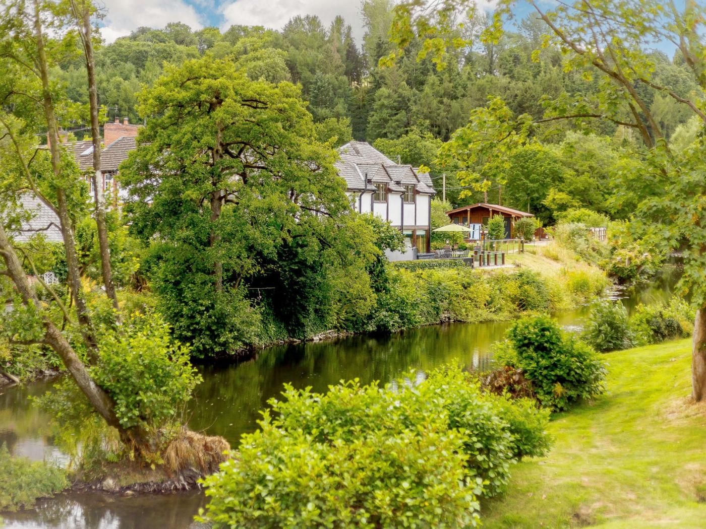 A riverside property with a house, a gazebo, and lush greenery.