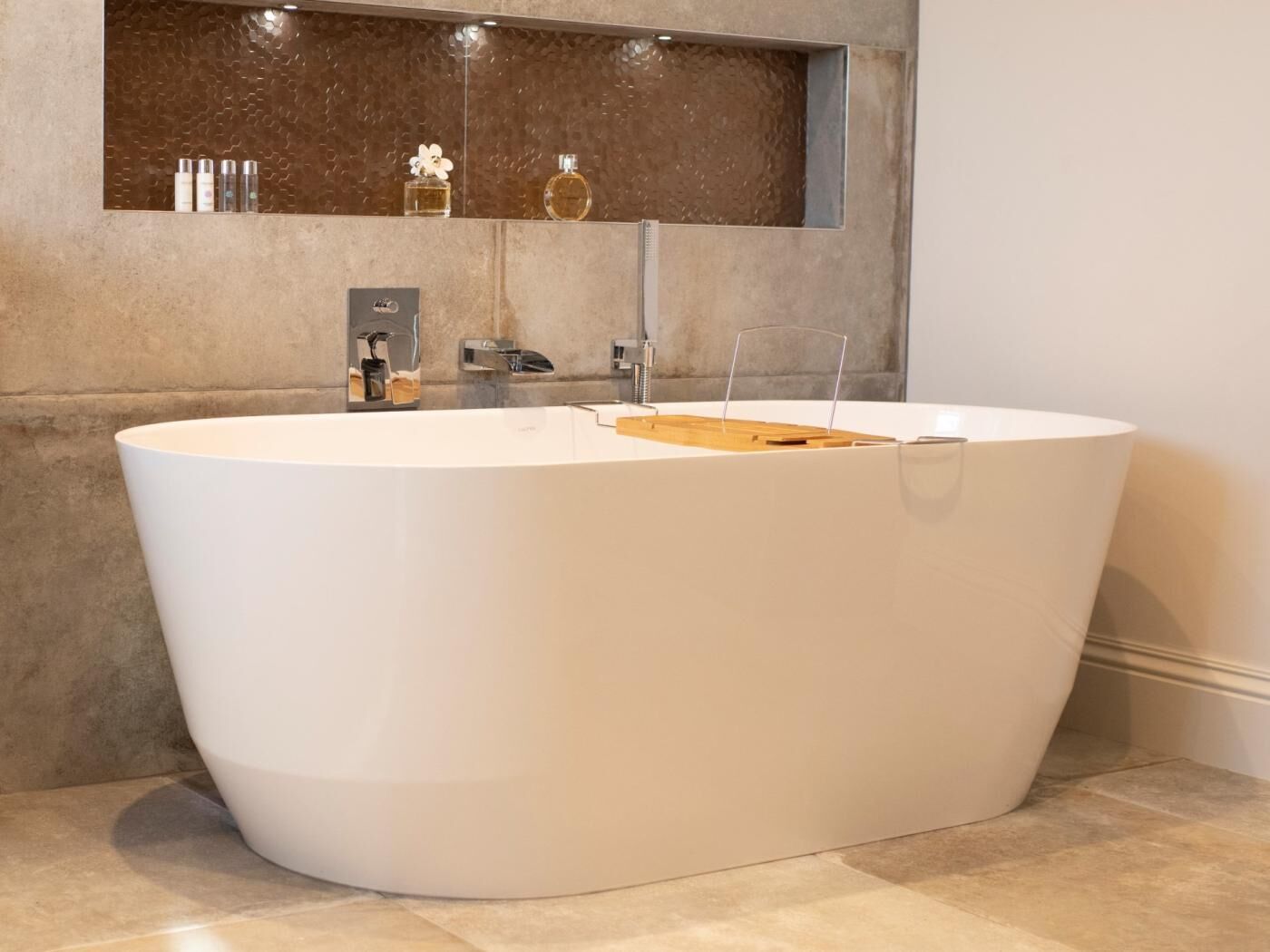 Un baño moderno con una bañera independiente, un espejo y un estante con artículos de aseo.