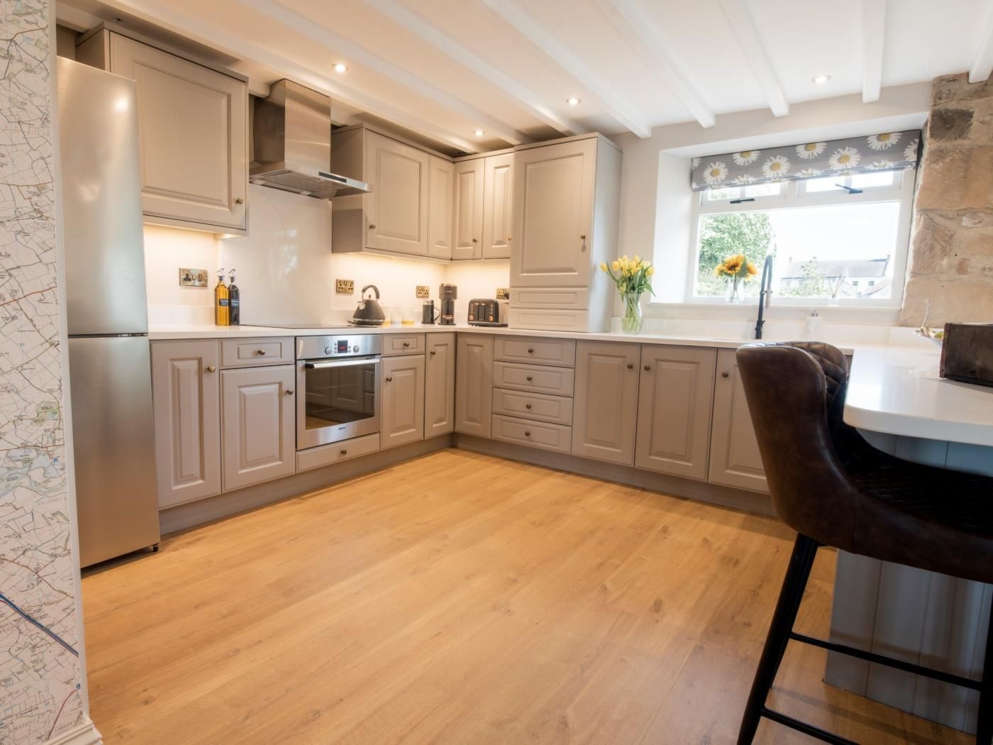 A modern kitchen with built-in appliances, wooden flooring, and a bar area.