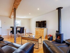 Ein Wohnzimmer mit Kamin, Fernseher und einem Essbereich mit Stühlen und Tisch.