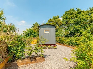 A small, single-story structure with a flat roof, surrounded by a gravel path and lush greenery. - 1 Bed in Canterbury (oc-88795) (Chillenden)