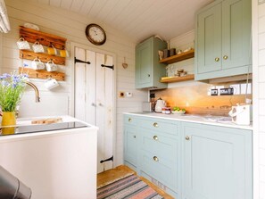 A kitchen with a clock, wooden shelves, a sink, and a coffee maker. - 1 Bed in Canterbury (oc-88795) (Chillenden)