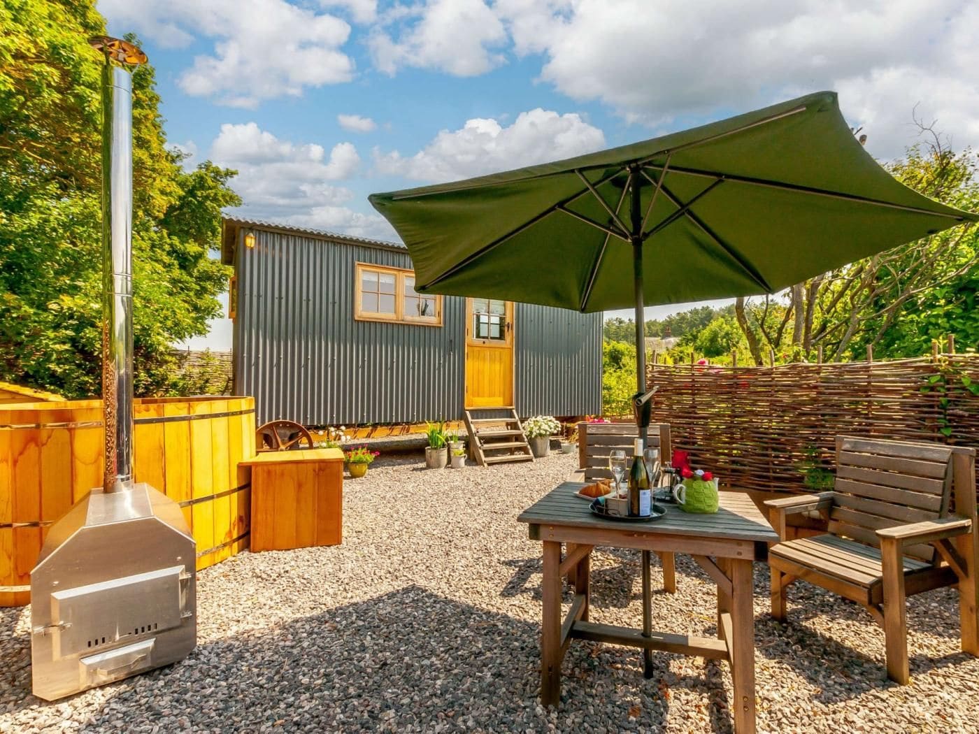 A patio area with a barbecue grill, wooden furniture, and a large umbrella.