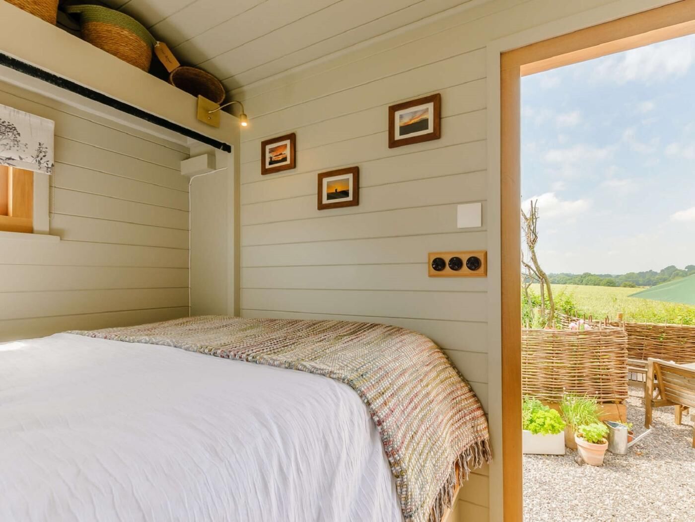 A bedroom with a bed, a wooden ceiling, and a view of a garden.