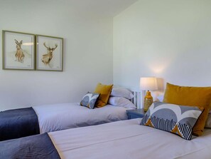 Una habitació d'hotel amb dos llits, una meseta de nit amb una làmpada i dos quadres amb imatges d'animals a la paret.