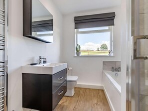 Un baño moderno con tocador, inodoro, bañera y ventana con vistas.