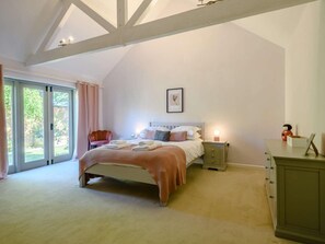 A bedroom with a large bed, a nightstand, a dresser, and a window with curtains. - 4 Bed in Melton Constable (oc-88678) (Briningham)