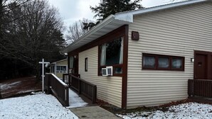 A single-story building with a covered porch, a small front yard, and a snow-covered ground. - Cozy 1-bedroom hotel room, Hamilton - #306 Mohawk (Hamilton)