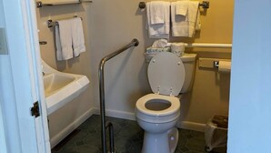 A bathroom with a toilet, a handrail, a sink, and a bathtub. - Cozy 1-bedroom hotel room, Hamilton - #306 Mohawk (Hamilton)