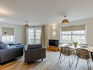 A modern living room with a sofa, armchair, dining table, and chairs. - 2 Bed in Braunton (oc-87750) (Croyde)