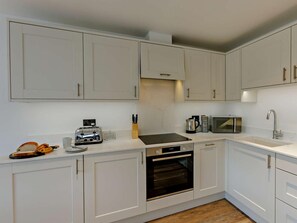 A modern kitchen with white cabinets, a built-in oven, a microwave, and a toaster. - 2 Bed in Braunton (oc-87750) (Croyde)