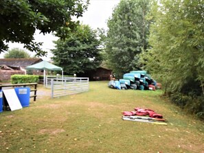 Ein grasbewachsenes Freigelände mit einer Umzäunung, Gepäck und einem grünen Zelt.