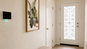 Un corridoio con una panchina, una porta con un pannello di vetro decorativo e una lampada a parete.