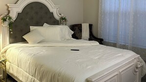 A bedroom with a large bed, a ceiling fan, a window with sheer curtains, and a nightstand with a lamp. - Bright apartment in a superb Virginia Beach location with AC (Virginia Beach)